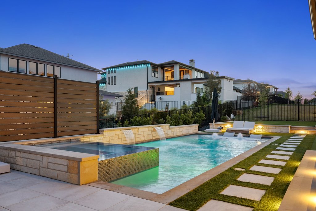 802 Geiger Path Austin, TX 78738 - Photo 1 of 40 Resort-style backyard featuring a pool and spa with water features, sun shelves for lounging, modern hardscape, and ambient lighting.