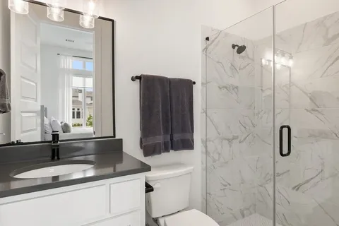 a bathroom with a granite countertop sink a toilet and shower