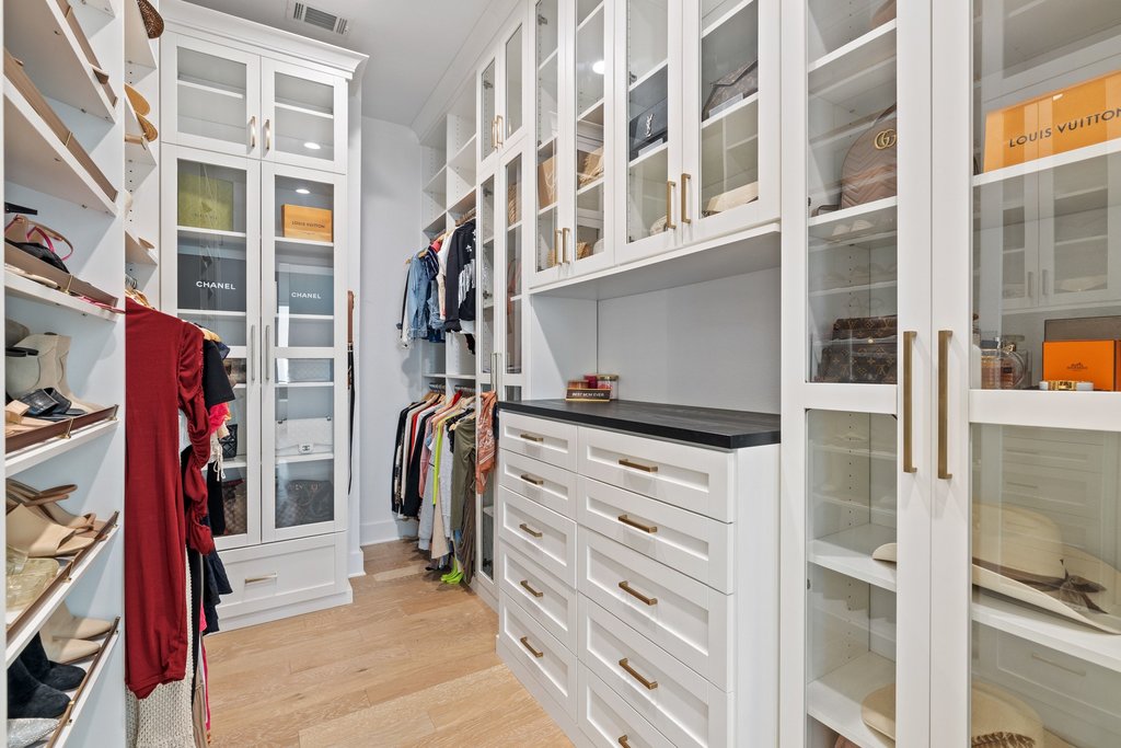802 Geiger Path Austin, TX 78738 - Photo 22 of 40 Primary bedroom walk in closet featuring custom built-in shelving and glass showcase cabinets.
