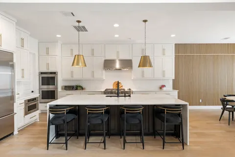 a kitchen with stainless steel appliances kitchen island granite countertop a table chairs stove and white cabinets