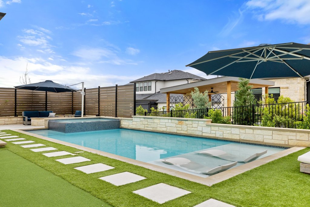 802 Geiger Path Austin, TX 78738 - Photo 31 of 40 Resort-style backyard featuring turf grass, a pool and spa with water features and sun shelves for lounging.
