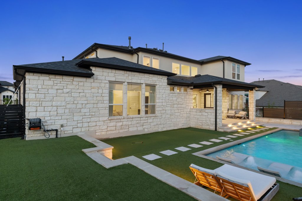 802 Geiger Path Austin, TX 78738 - Photo 33 of 40 Backyard at dusk featuring a resort-style pool and spa, sun shelves for lounging, and a putting green! Perfect for entertaining and outdoor living.