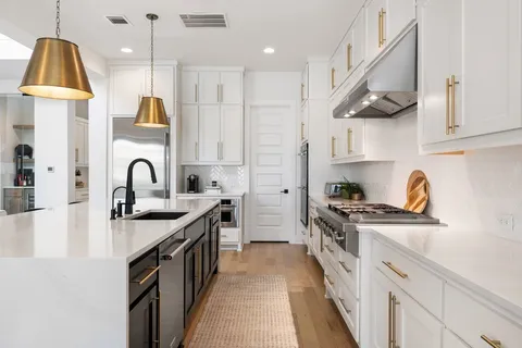 a kitchen with stainless steel appliances granite countertop a sink a stove and a wooden floors