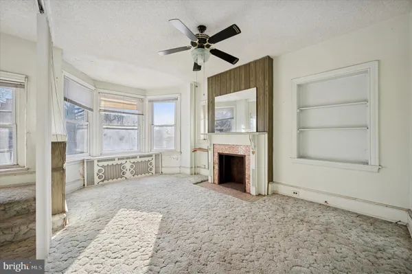 a view of a livingroom with furniture and a fireplace a ceiling fan and wooden floor