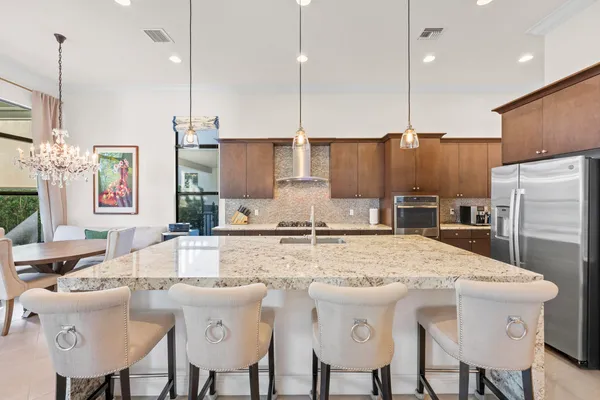 a living room with stainless steel appliances kitchen island granite countertop furniture and a chandelier