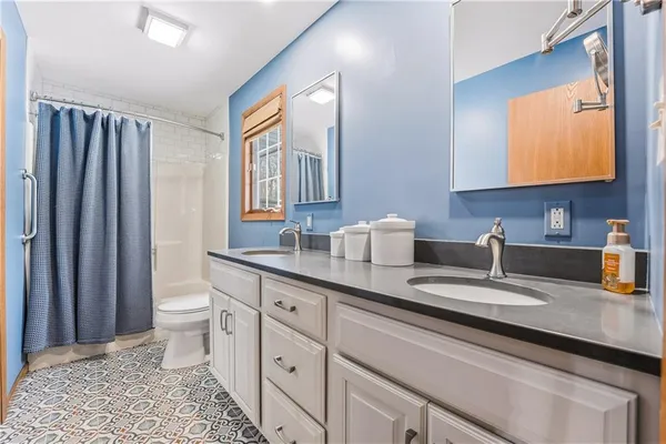 a bathroom with a double vanity sink toilet and a mirror