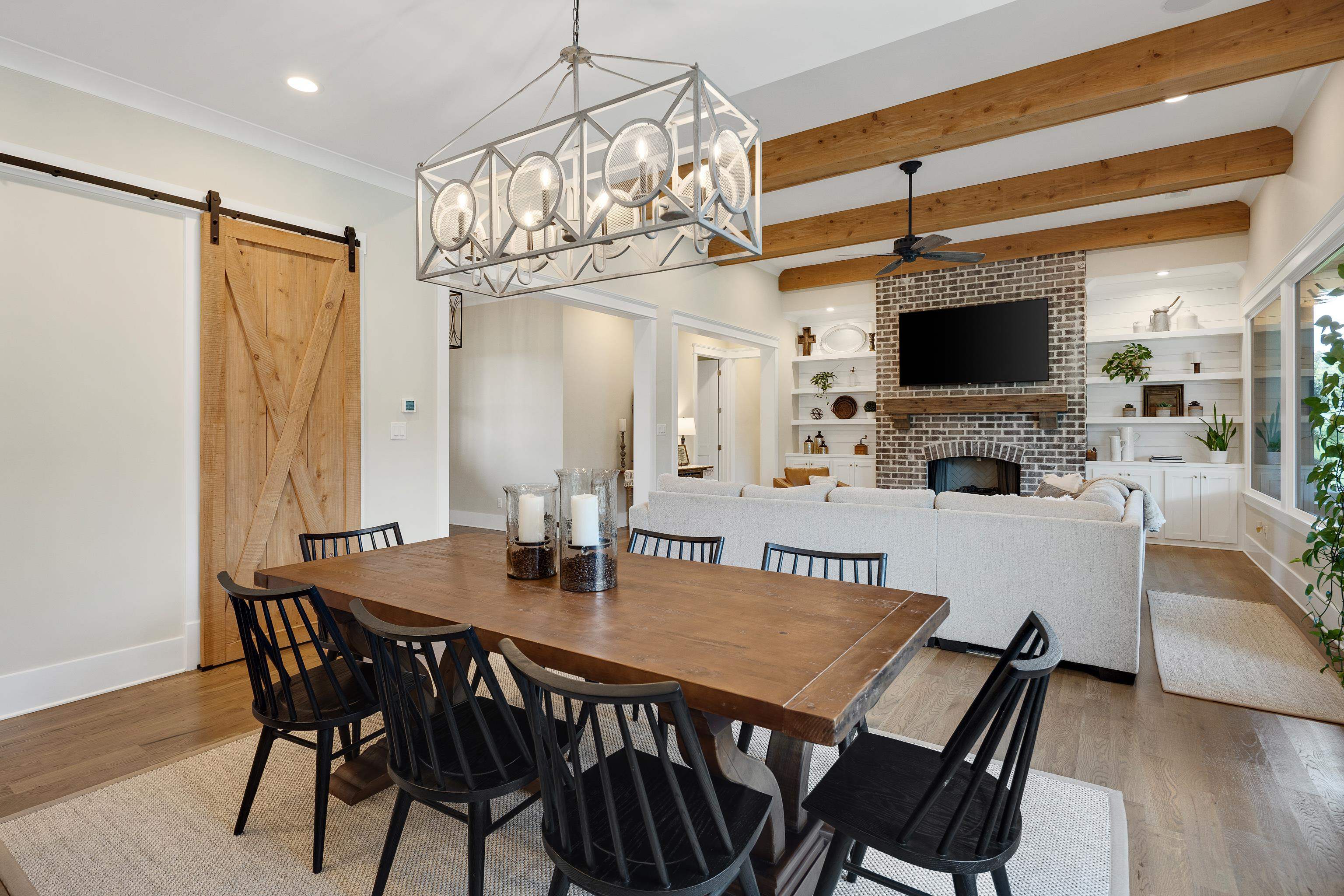 805 Shady Grove Road Williston, TN 38076 - Photo 14 of 40 Open-concept living area featuring exposed wood beams, a brick fireplace, built-in shelving, wood-finish flooring, and a sliding barn door