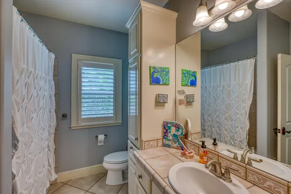 a bathroom with a granite countertop sink a toilet a mirror a vanity and shower
