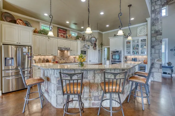 a kitchen with stainless steel appliances granite countertop a kitchen island a stove a kitchen island a dining table and chairs