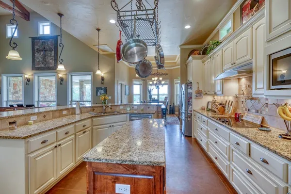 a large kitchen with stainless steel appliances granite countertop a lot of counter space and wooden floor
