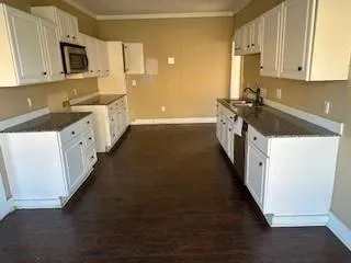 a kitchen with granite countertop a sink a stove oven a counter top space and cabinets