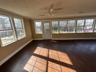 a view of an empty room with wooden floor and a window