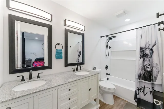 a bathroom with a granite countertop sink mirror vanity and toilet