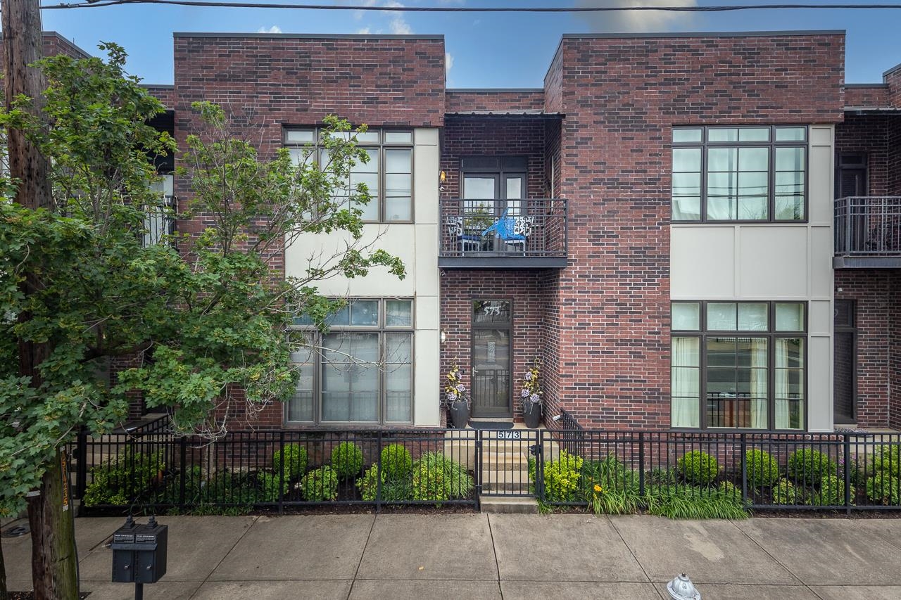 front view of a brick house with a yard and plants