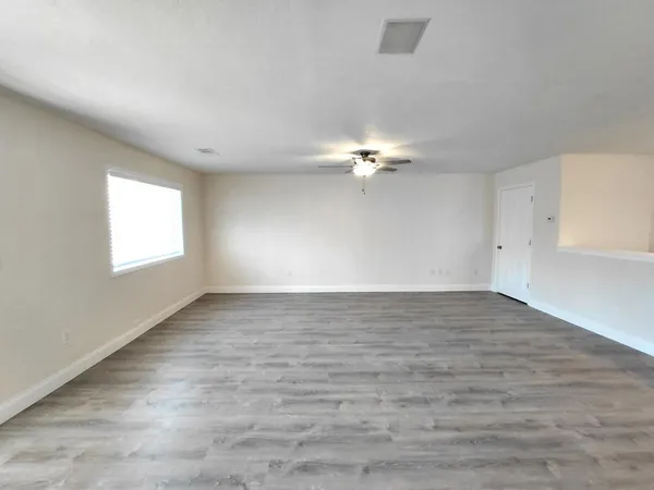 a view of an empty room with chandelier fan and window