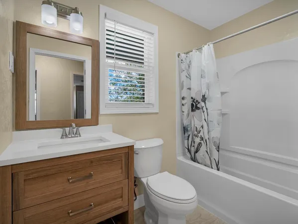 a bathroom with a granite countertop sink toilet a mirror and shower
