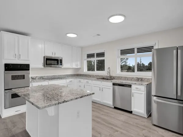 a kitchen with stainless steel appliances granite countertop a stove a sink and a refrigerator