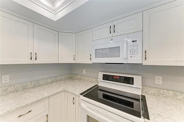 a kitchen with granite countertop white cabinets and white appliances