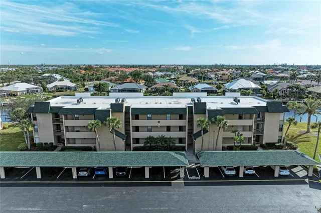 a front view of a building with lot of cars and trees