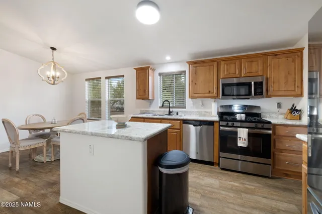 a kitchen with stainless steel appliances granite countertop a refrigerator a sink dishwasher a stove with wooden cabinets and wooden floor