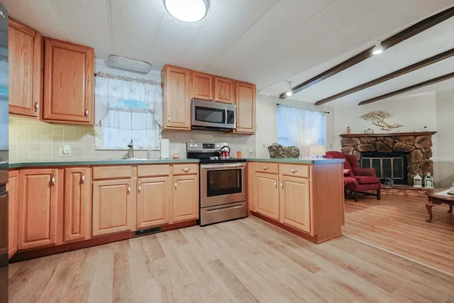 a kitchen with stainless steel appliances granite countertop a stove top oven a sink dishwasher and a microwave oven with wooden floor