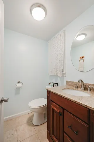 a bathroom with a granite countertop toilet sink mirror and vanity