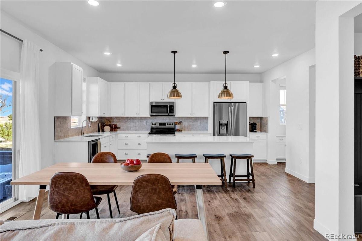 5453 Inland Avenue Firestone, CO 80504 - Photo 11 of 49 a kitchen with stainless steel appliances granite countertop a stove top oven a refrigerator a sink and a dining table with wooden floor