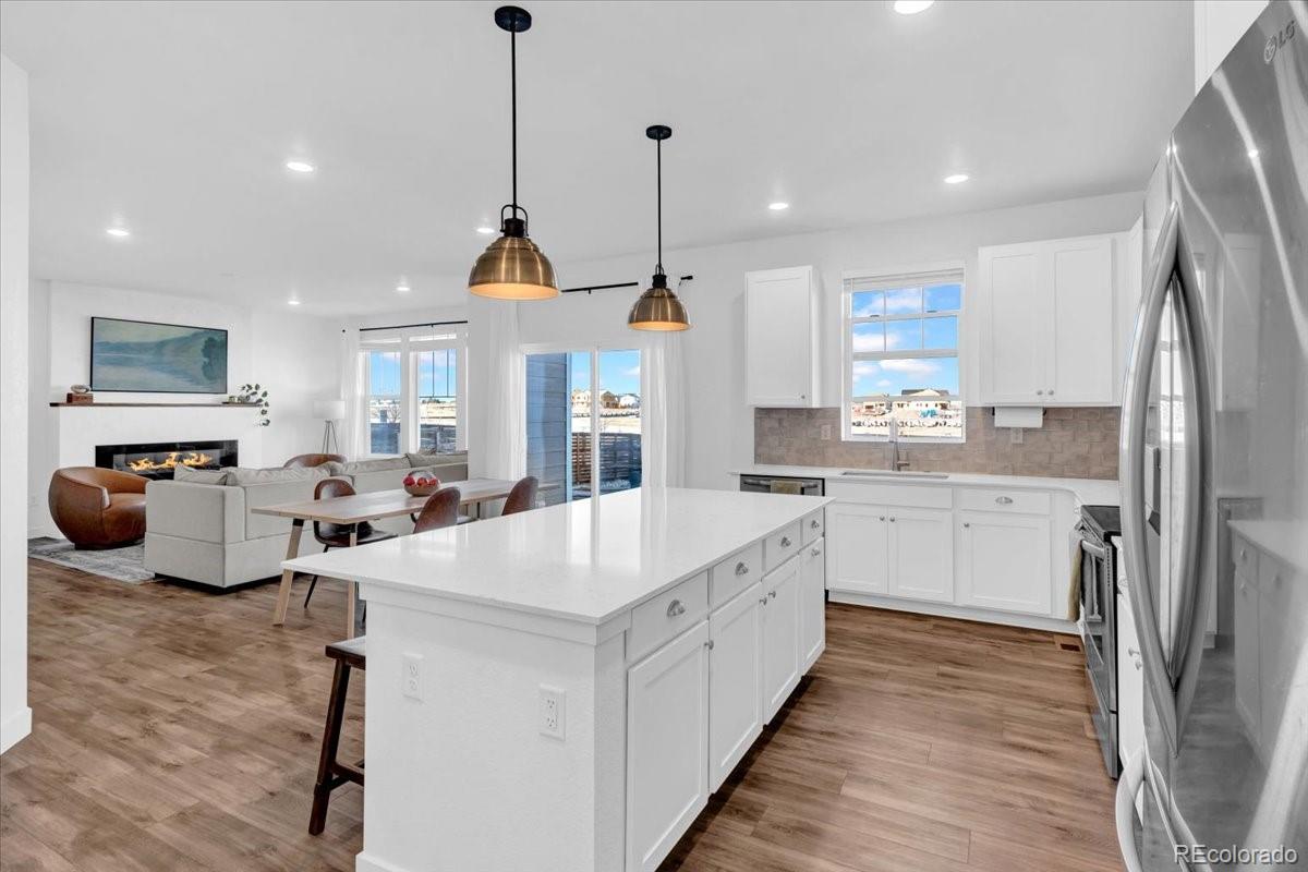 5453 Inland Avenue Firestone, CO 80504 - Photo 14 of 49 a large kitchen with kitchen island a stove a sink a center island and windows