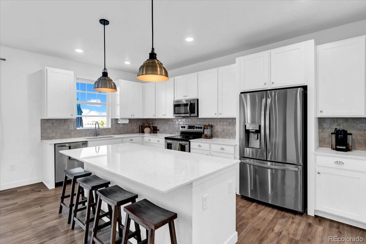 5453 Inland Avenue Firestone, CO 80504 - Photo 15 of 49 a kitchen with stainless steel appliances a stove a refrigerator a sink a stove a table and chairs