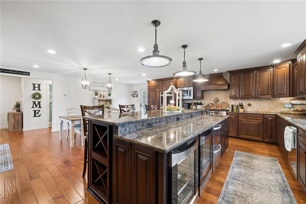 55 Spring Valley Drive Washington, PA 15301 - Photo 9 of 36 a kitchen with stainless steel appliances granite countertop a kitchen island a stove a refrigerator a sink a dining table and chairs with wooden floor