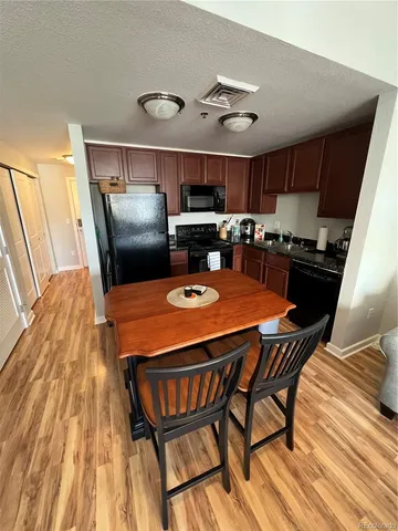 a kitchen with stainless steel appliances granite countertop a stove a refrigerator a sink dishwasher a dining table and chairs with wooden floor