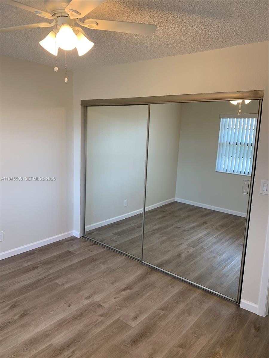 9273 Southwest 8th Street, Unit 411 Boca Raton, FL 33428 - Photo 11 of 21 an empty room with windows and ceiling fan