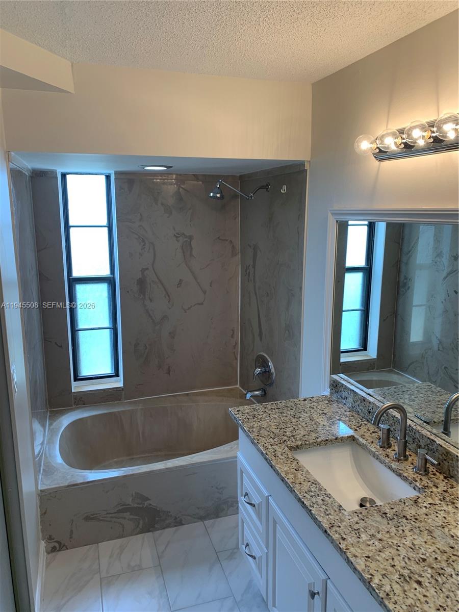 9273 Southwest 8th Street, Unit 411 Boca Raton, FL 33428 - Photo 12 of 21 a bathroom with a granite countertop bathtub shower sink and mirror