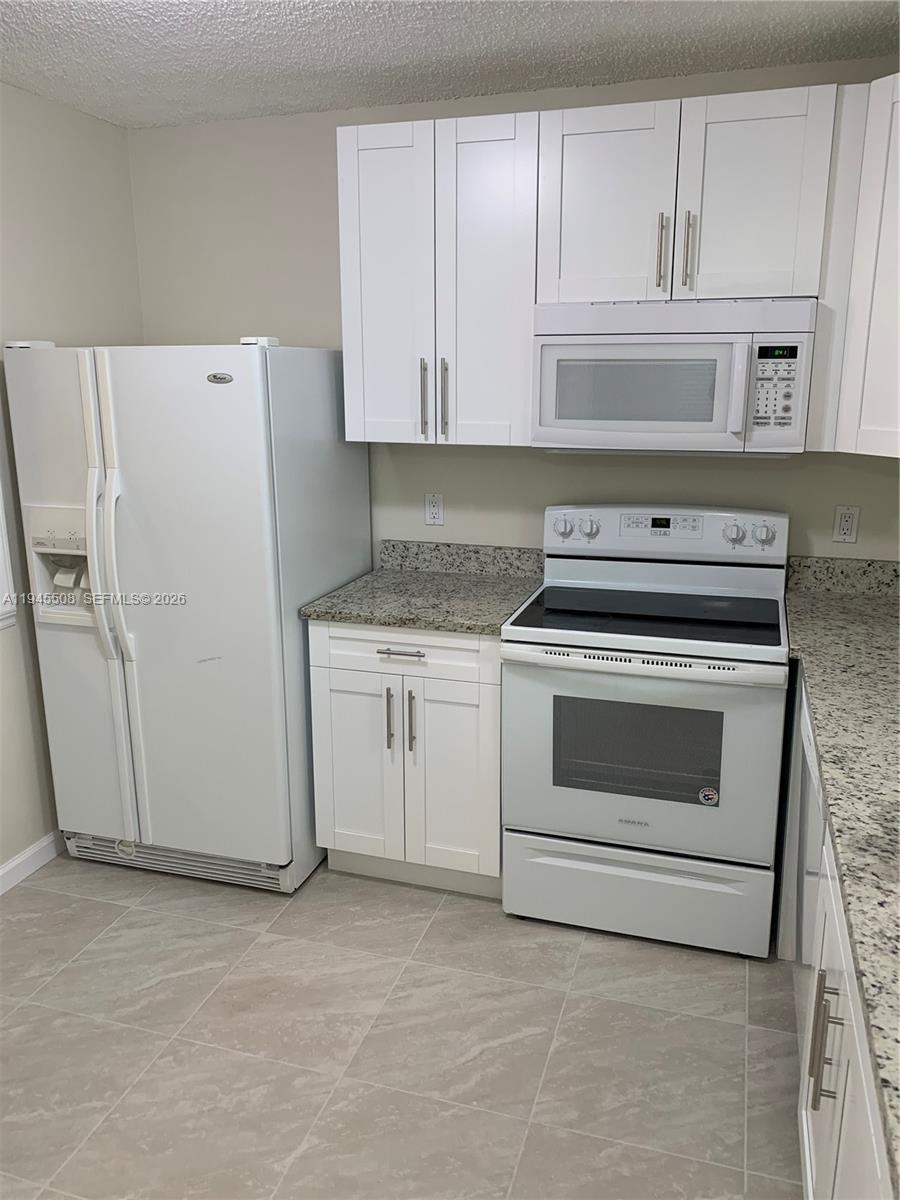 9273 Southwest 8th Street, Unit 411 Boca Raton, FL 33428 - Photo 6 of 21 a kitchen with cabinets appliances and a counter space