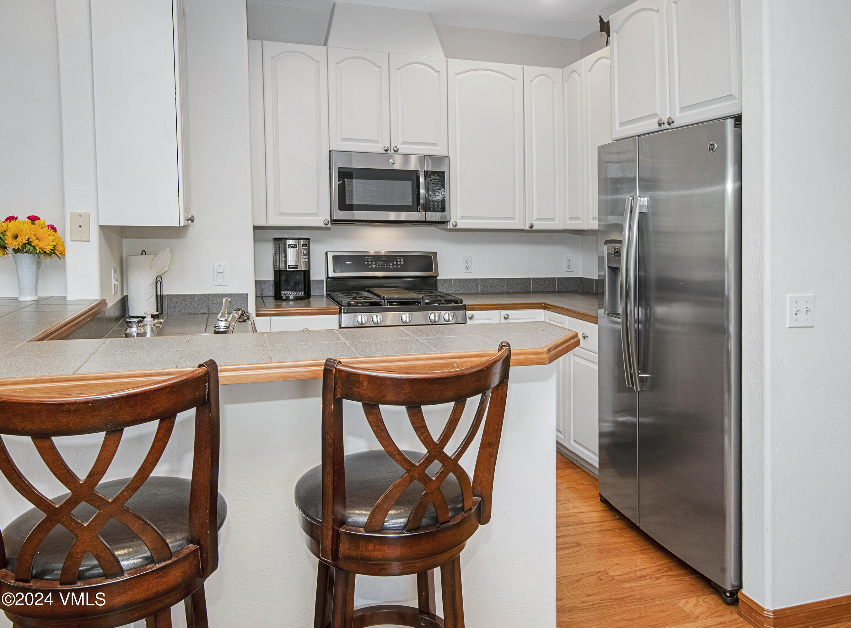 751 Singletree Road, Unit 3N Edwards, CO 81632 - Photo 18 of 35 a kitchen with stainless steel appliances granite countertop a refrigerator a stove a sink and a dining table with wooden floor