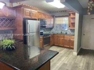 5500 Southwest 77th Court, Unit 201 Miami, FL 33155 - Photo 2 of 3 a kitchen with stainless steel appliances granite countertop a refrigerator a sink and a stove