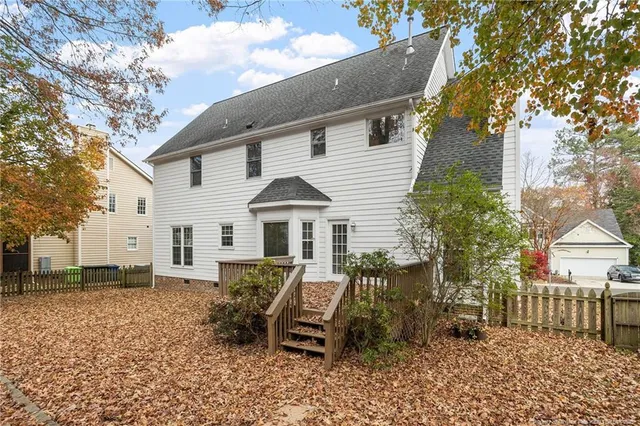 a view of a white house with a yard and lawn chairs under a large tree