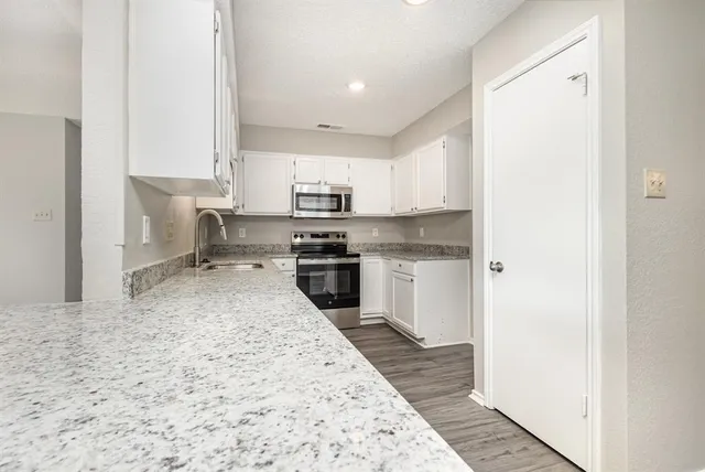 a kitchen with stainless steel appliances granite countertop a refrigerator sink and white cabinets