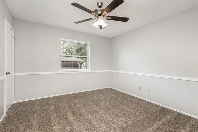 an empty room with a window and a ceiling fan