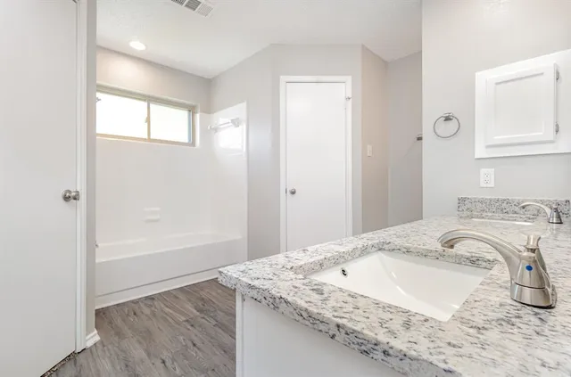a bathroom with a granite countertop sink a mirror and a bathtub