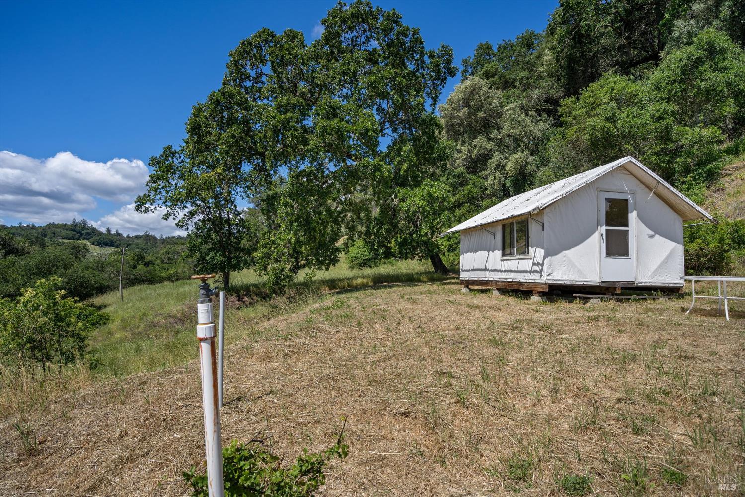1077 Westside Road Healdsburg, CA 95448 - Photo 29 of 48 a backyard of a house with table and chairs under an umbrella
