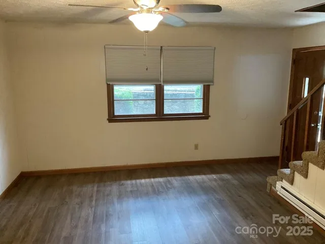 an empty room with wooden floor fan and window