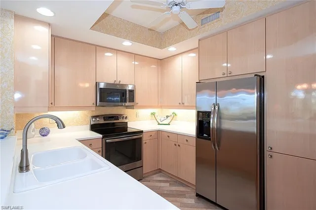 a kitchen with stainless steel appliances granite countertop a sink a stove a refrigerator a washer dryer and cabinets