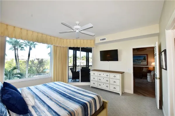 a bedroom with a bed a flat screen tv and a large window