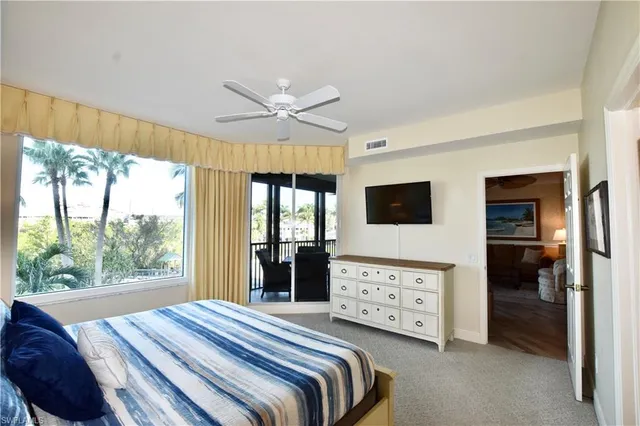 a bedroom with a bed a flat screen tv and a large window