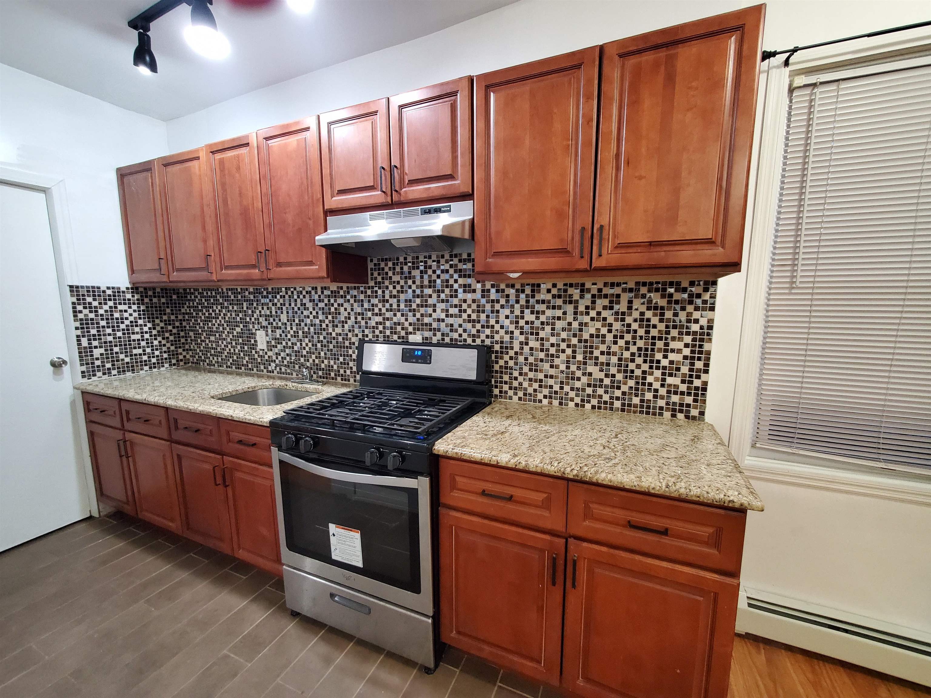 140 West 3rd Street, Unit 1 Bayonne, NJ 07002 - Photo 2 of 8 a kitchen with granite countertop stainless steel appliances wooden cabinets and a sink