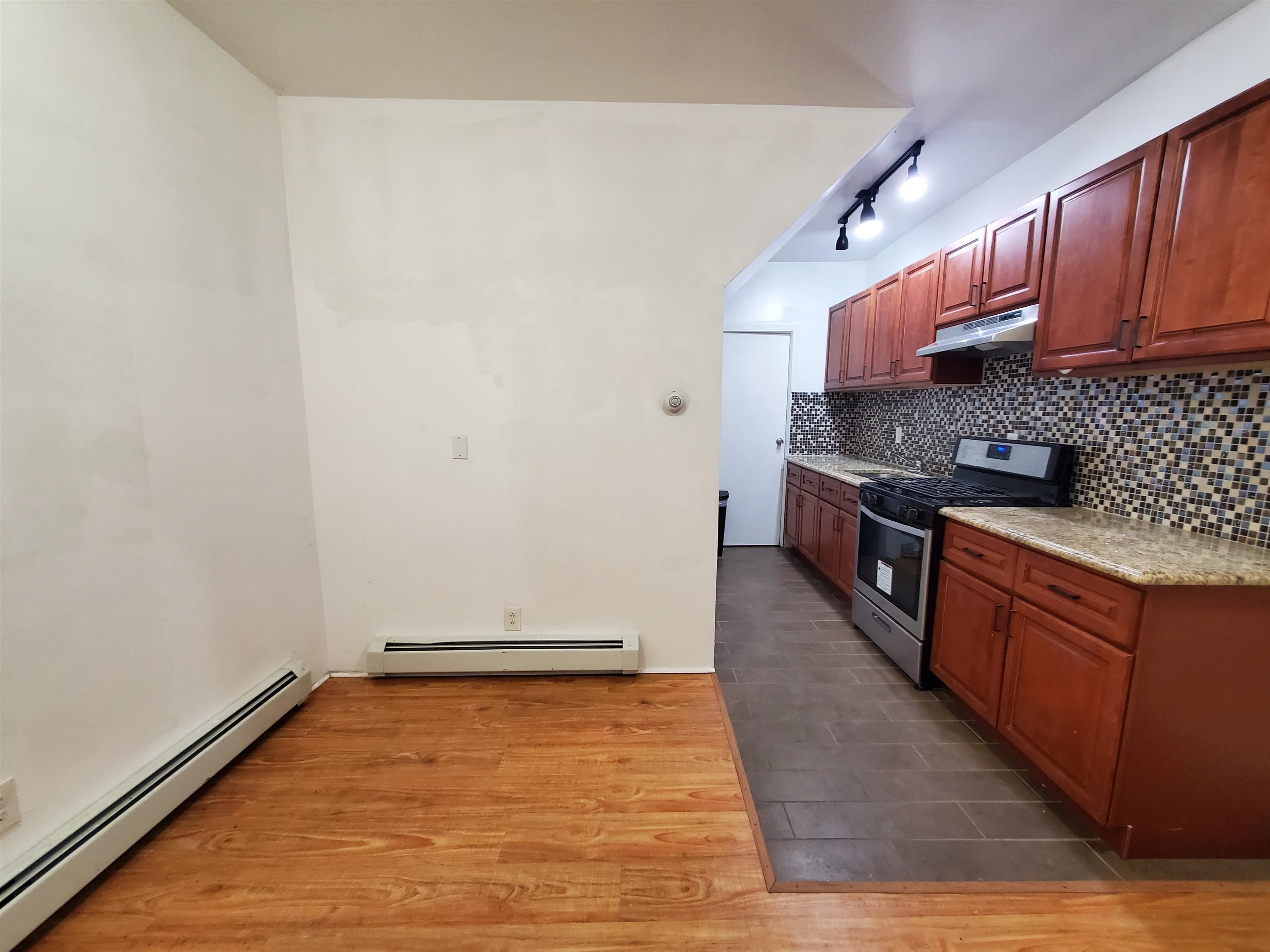 140 West 3rd Street, Unit 1 Bayonne, NJ 07002 - Photo 7 of 8 a kitchen with stainless steel appliances granite countertop a stove a sink and a refrigerator