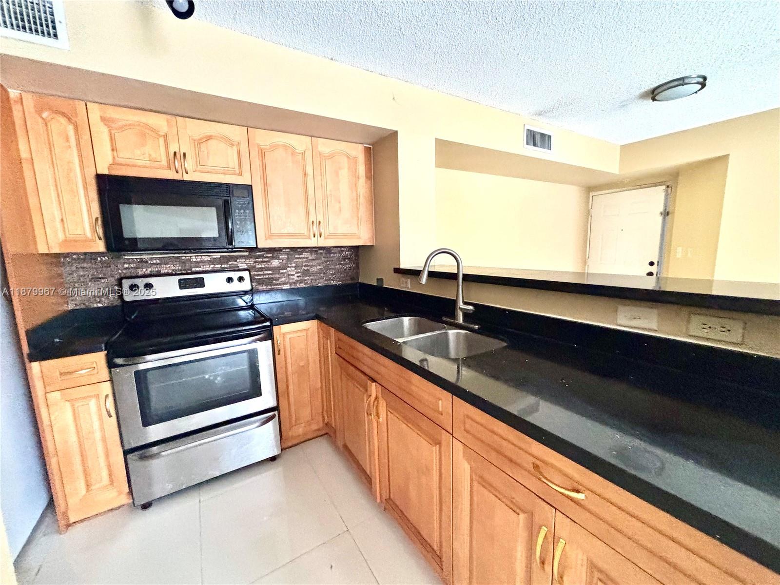 777 Southwest 111th Way, Unit 101 Pembroke Pines, FL 33025 - Photo 4 of 7 a kitchen with granite countertop a sink stainless steel appliances and cabinets