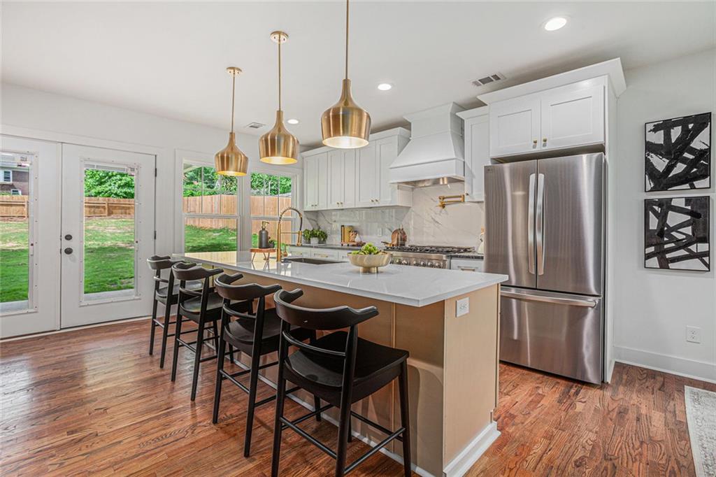 1721 South Gordon Street Southwest Atlanta, GA 30310 - Photo 15 of 44 a kitchen with stainless steel appliances granite countertop a stove a refrigerator a sink dishwasher a dining table and chairs with wooden floor