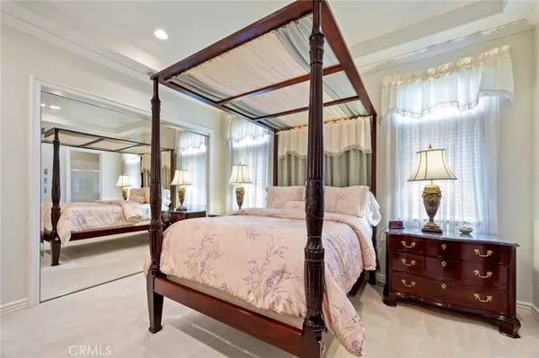 a bedroom with a bed and a large mirror with a dresser